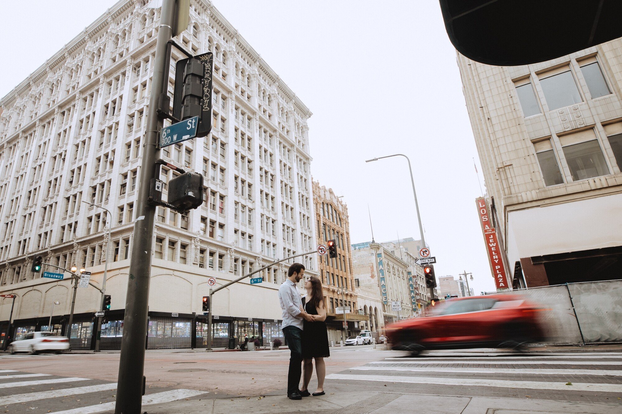 couple standing together on street as car passes by